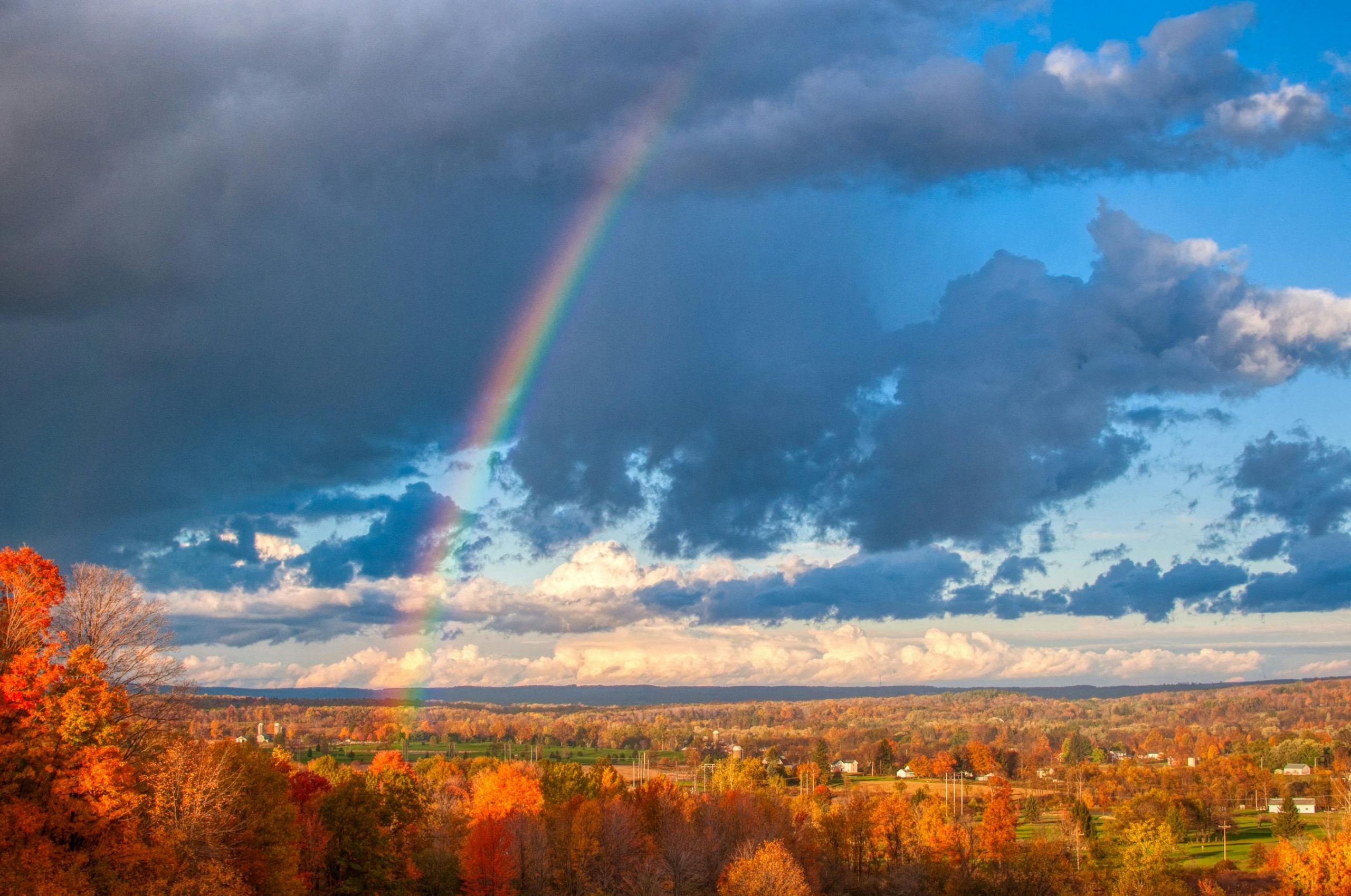 Vibrant rainbow arcs over scenic autumn landscape in Venango, PA.