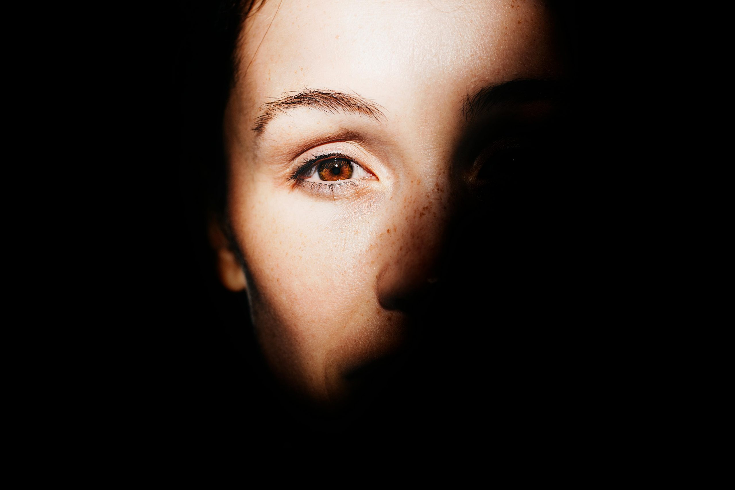 A striking portrait highlighting a woman's eye with dramatic light and shadow play.